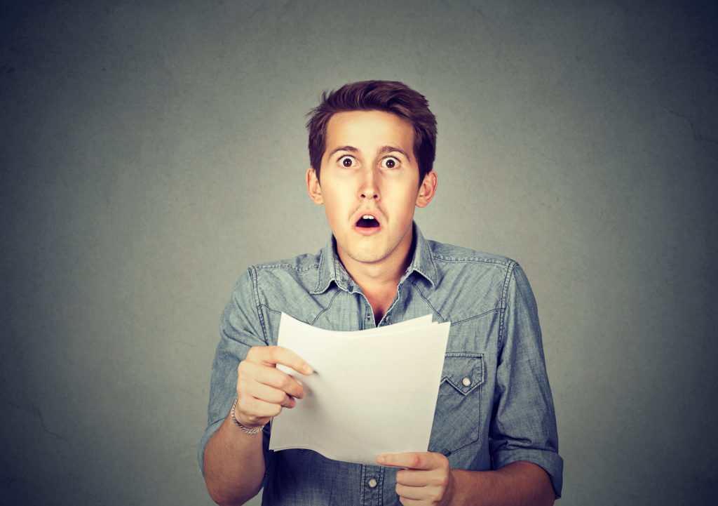 Man Holding A Piece Of Paper With Panicked Look Gettyimages 807540098